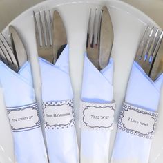 silverware and napkins are sitting on a white plate with blue napkins that say i love you