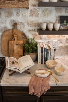 an open book sitting on top of a kitchen counter next to some bowls and books