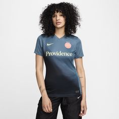 a woman with curly hair standing in front of a white background wearing a blue shirt that says providence