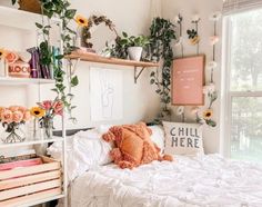 a white bed sitting next to a window filled with books and plants on top of it