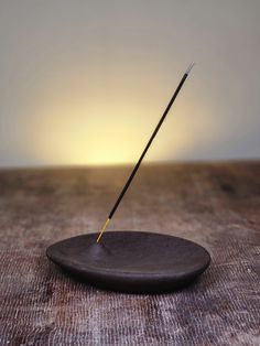 a wooden plate with a stick sticking out of it on a table next to a light