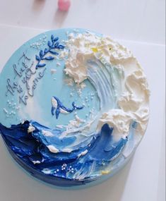 there is a blue cake with white frosting on the top and waves in the middle