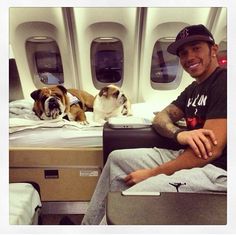 a man sitting in an airplane with his dog on the bed next to him and looking at the camera