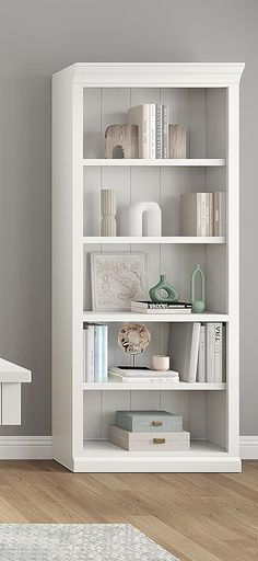 a white book shelf with books and other items on it in the corner of a room