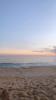 an empty beach at sunset with the ocean in the background