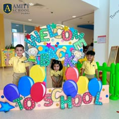 three children are posing in front of a welcome to school sign with balloons on it