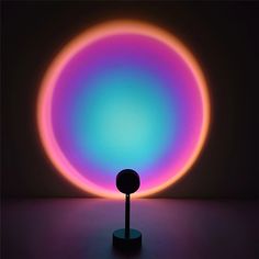 an illuminated object on a table in the dark with a purple and blue circle behind it