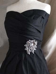 a black dress with a silver brooch on it