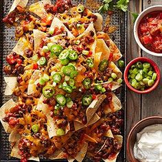 an overhead view of nachos with salsa and sour cream sauce on the side