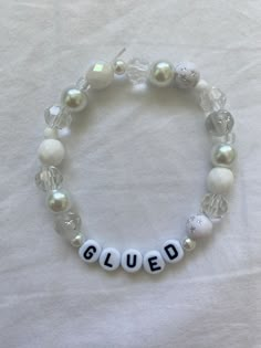 a white beaded bracelet with beads that spell out the word glued on it