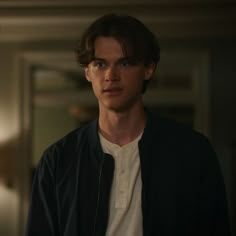 a young man standing in front of a mirror wearing a black jacket and white t - shirt