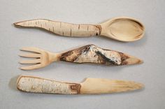 three wooden utensils with mountains carved on them, one in the shape of spoons