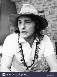 a black and white photo of a man wearing a hat with beads around his neck