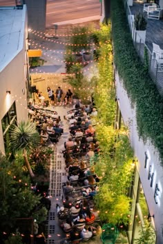 an overhead view of people sitting at tables in the middle of a courtyard with string lights