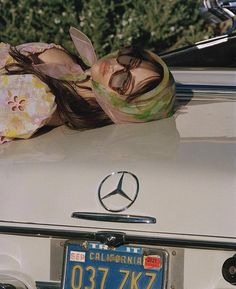 a woman laying on the hood of a car