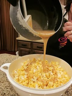 a woman pours orange juice into a bowl of popcorn