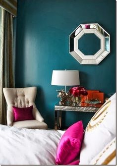 a white chair sitting next to a bed under a mirror mounted on the side of a wall