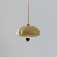 a white light hanging from a ceiling with a brown bead on it's end