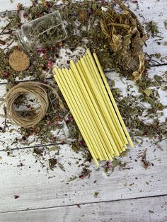 several yellow sticks sitting on top of a wooden table next to some dried herbs and twine