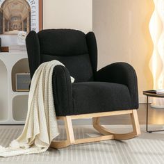 a black chair with a blanket on top of it next to a coffee table and lamp