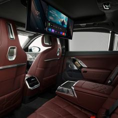 the interior of a luxury car with red leather seats and entertainment system on the wall