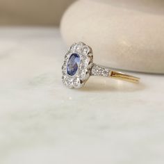 Un beau saphir taille coussin en serti clos perlé avec un entourage de diamants en serti festonné. Les pierres sont serties sur platine et le corps de bague est en or jaune 18K. Une bague pompadour réalisée dans la plus pure tradition de la joaillerie française, conçue pour être transmise de génération en génération. Pierres : Au centre un saphir de 1,24 carat, entouré de 10 diamants taille brillant pour 1,15 carat. Sur la descente de l'anneau, de chaque coté, deux diamants taille brillant. Mont Pompadour, New Era, Weddings