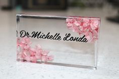 pink flowers are in the middle of a clear acrylic block that says dr michael landa