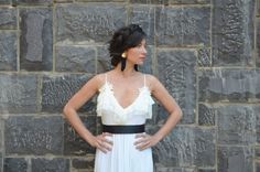 a woman standing in front of a stone wall with her hands on her hips, wearing a white and black dress