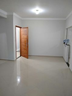 an empty room with white walls and tile flooring, doors open to the outside