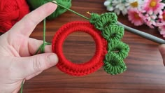 someone is crocheting an ornament with yarn on a table next to flowers