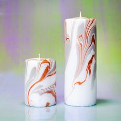 two white candles sitting next to each other on a table