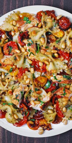 a white plate topped with pasta and veggies on top of a wooden table