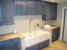 a bathroom with gray cabinets and a white bathtub in the middle of the room