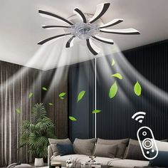 a living room filled with furniture and green leaves on the wall above it is a ceiling fan