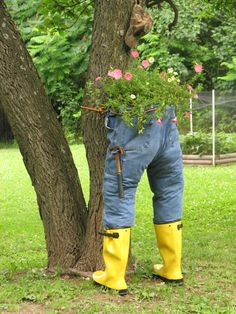 a pair of yellow rain boots hanging from the side of a tree with flowers in it