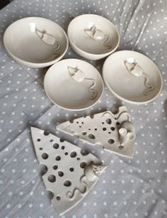 five pieces of white pottery sitting on top of a polka dot covered bed with blue and white dots