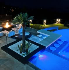 an outdoor dining area next to a pool at night