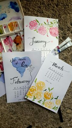 four calendars with flowers on them sitting next to paintbrushes and watercolor paints