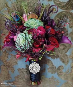 a bouquet of flowers sitting on top of a blue table cloth covered wallpaper in front of a gold damask background