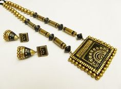 a gold and black beaded necklace with matching earring set on a white surface