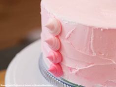 a pink frosted cake sitting on top of a white plate