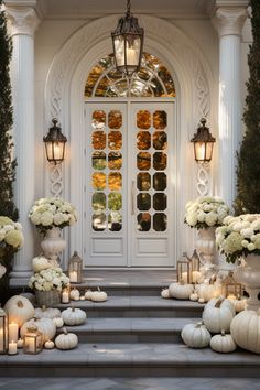 an entrance decorated with white flowers and pumpkins, candles and vases on the steps