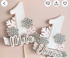 two cake toppers with the number one and snowflakes on them