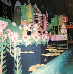 an artistic display with paper flowers and people in the water at night, surrounded by other art pieces