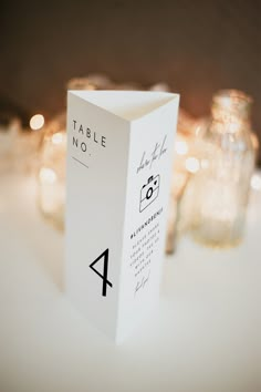 a table number is placed on top of a white box with candles in the background