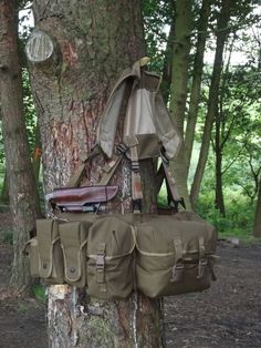 the back pack is attached to the trunk of a tree with other items hanging from it