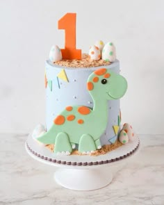 a birthday cake decorated with a dinosaur and an orange number one on it's top