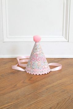 a small pink and white hat sitting on top of a wooden floor next to a door