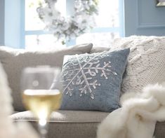 a glass of wine sitting on top of a couch in front of a snowflake pillow