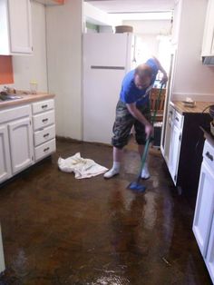 a man is cleaning the kitchen floor with a mop and dust cloth on it